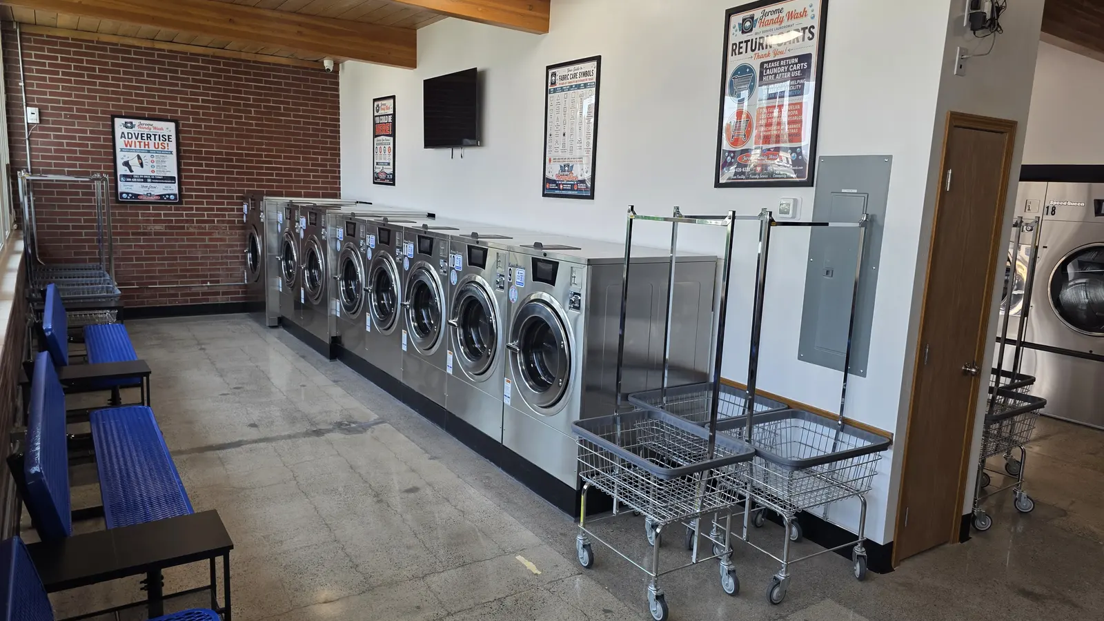 Seating benches and laundry carts across from the washer row inside Jerome Handy Wash