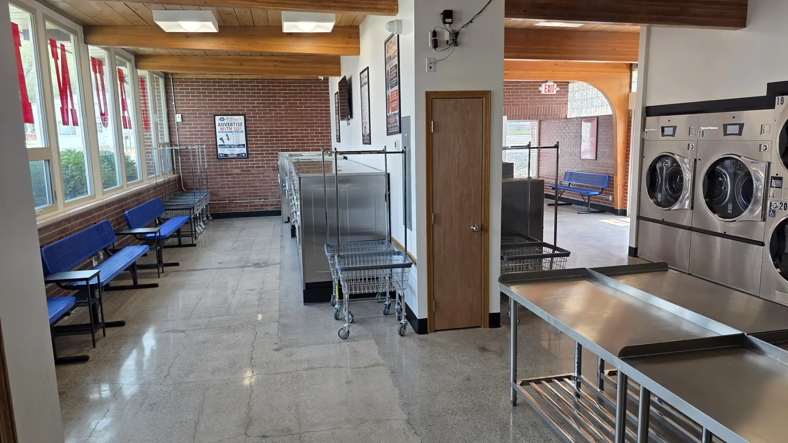 A wide view of the seating area at Jerome Handy Wash with benches, exposed brick, wood beam ceiling, and natural light from the window wall